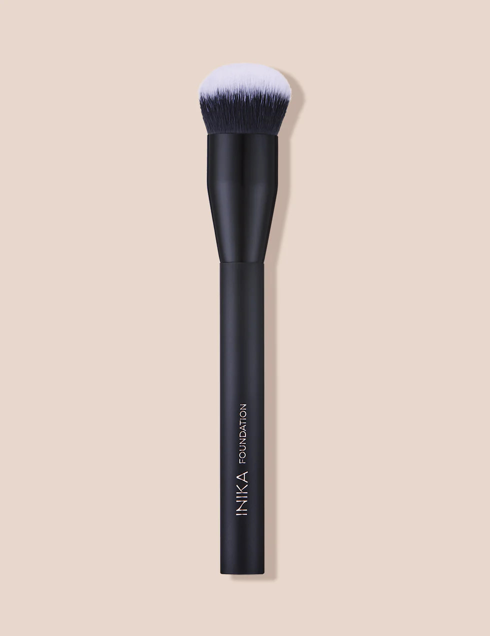Musta meikkisivellin, jossa valkoinen harjaspää, taustalla vaalea beige pohja.